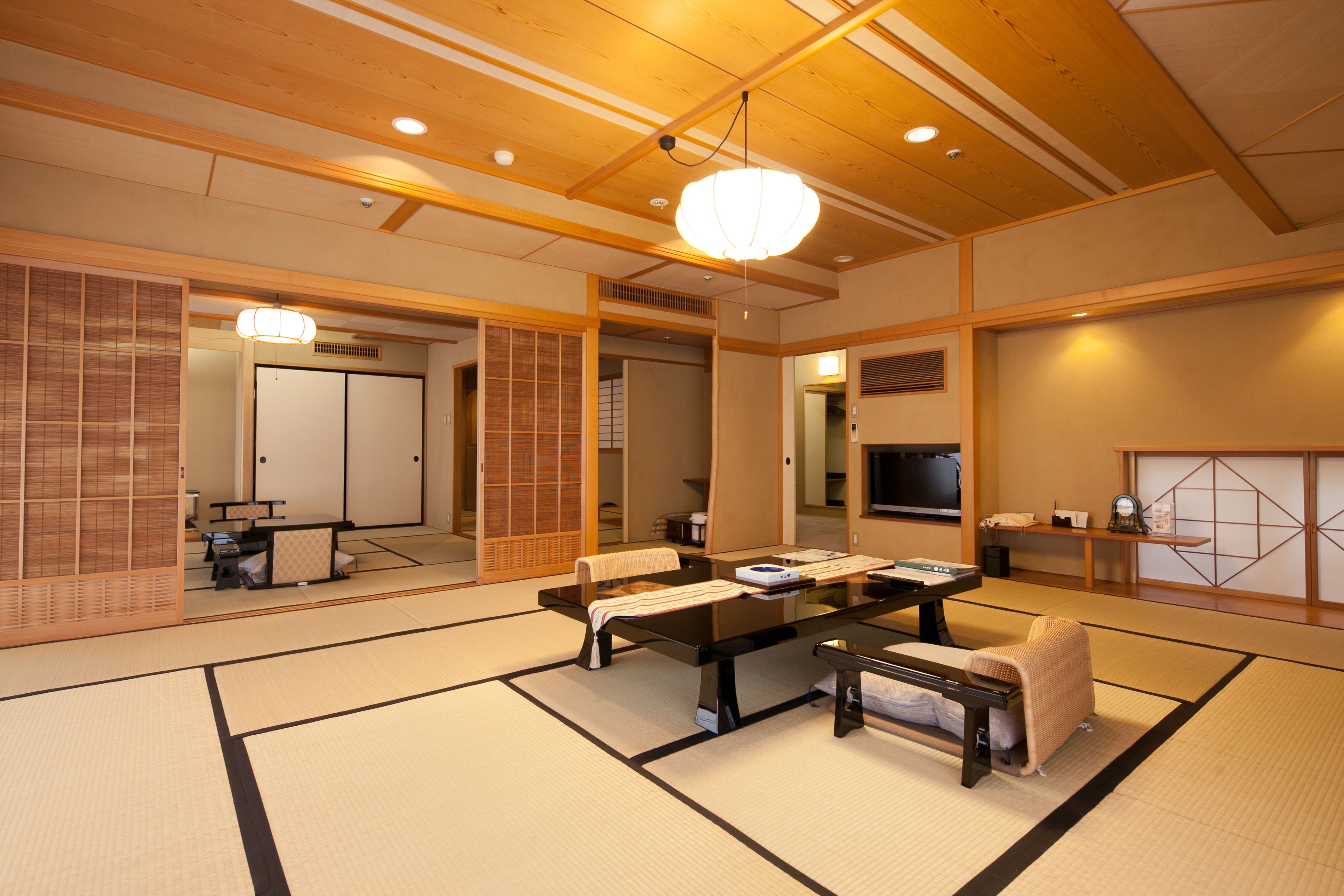 Ein traditioneller japanischer Raum mit Tatami-Bodenbelag, einem niedrigen Tisch mit Kissen und Schiebetüren.