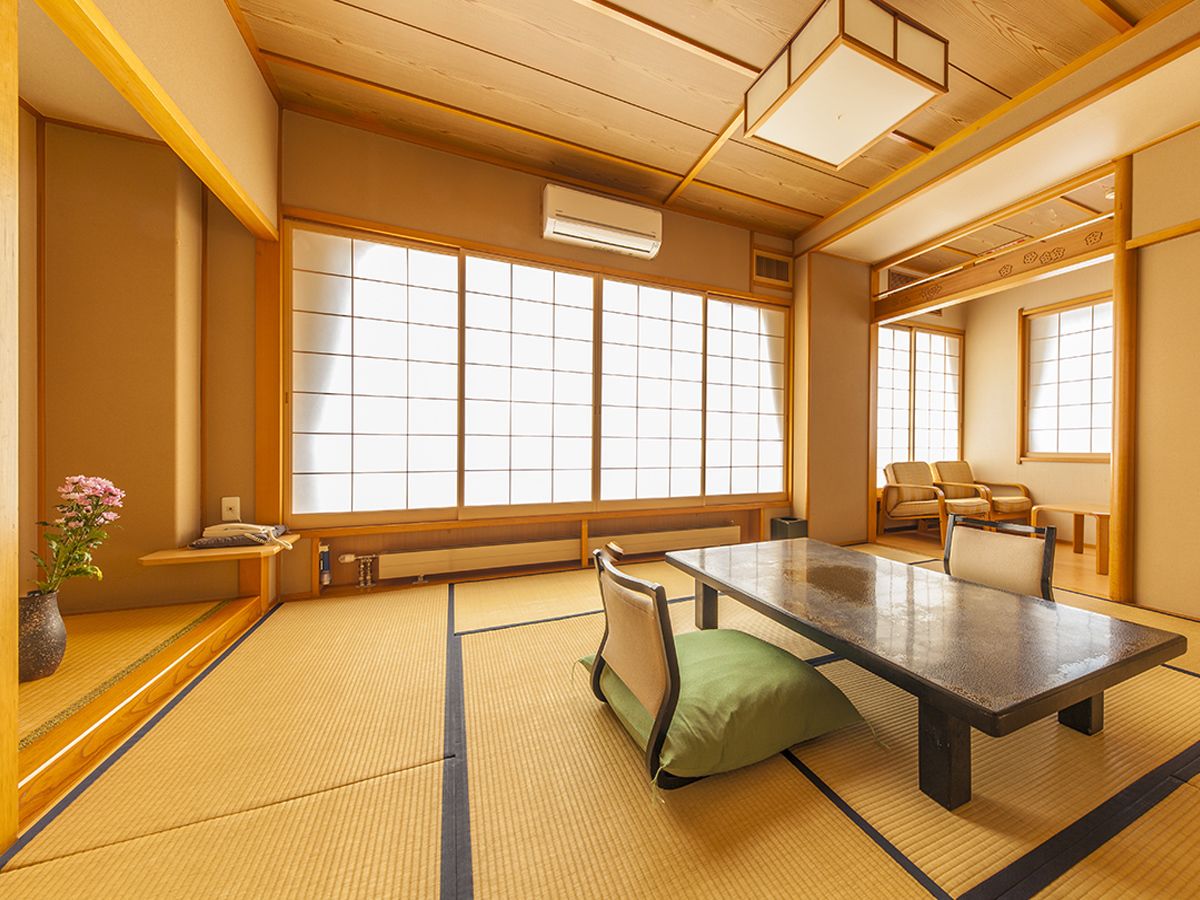 Um quarto japonês tradicional com tatames, uma mesa baixa e portas deslizantes.