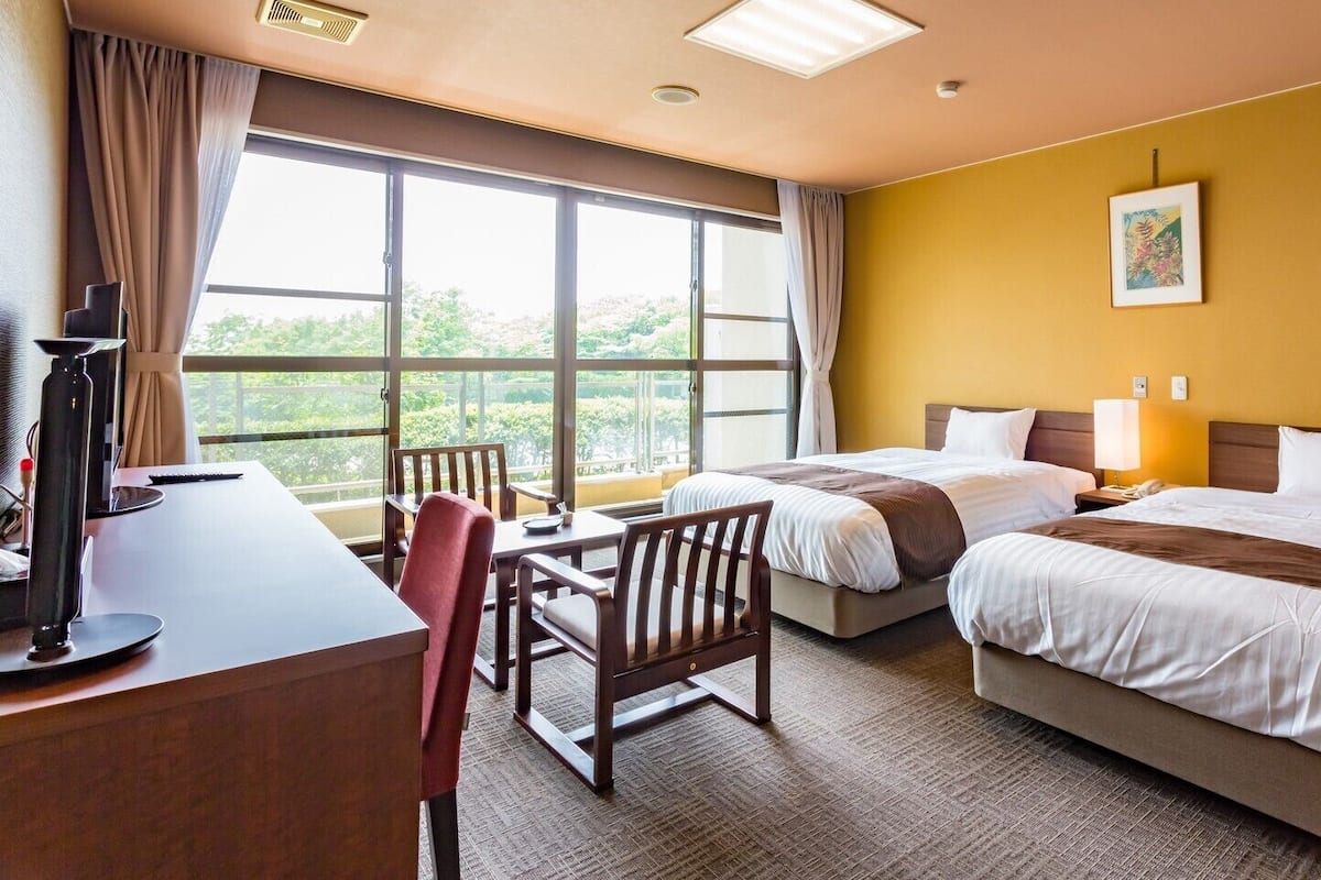 Habitación de hotel con dos camas, un escritorio y una silla.