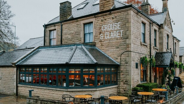 A stone building with a sign reading "The Grouse & Claret." It features a corner window with multiple tables and chairs outside. - Grouse & Claret, Derby by Marston's Inns (Matlock)