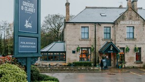 A stone building with a sign for 'The Grouse & Claret' pub, rooms, and caravan park. - Grouse & Claret, Derby by Marston's Inns (Matlock)