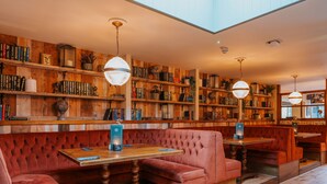 A cozy restaurant with wooden bookshelves, red upholstered booths, and pendant lighting. - Grouse & Claret, Derby by Marston's Inns (Matlock)