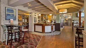 A bar area with a checkered floor, wooden bar counter, and bar stools. - The Blue Bell (Middlesbrough)