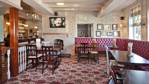 A bar area with wooden furniture, a brick wall, and a patterned carpet. - The Blue Bell (Middlesbrough)