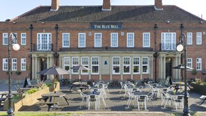 A brick building with a sign reading 'The Blue Bell Hotel.' There are outdoor tables and chairs arranged in front. - The Blue Bell (Middlesbrough)