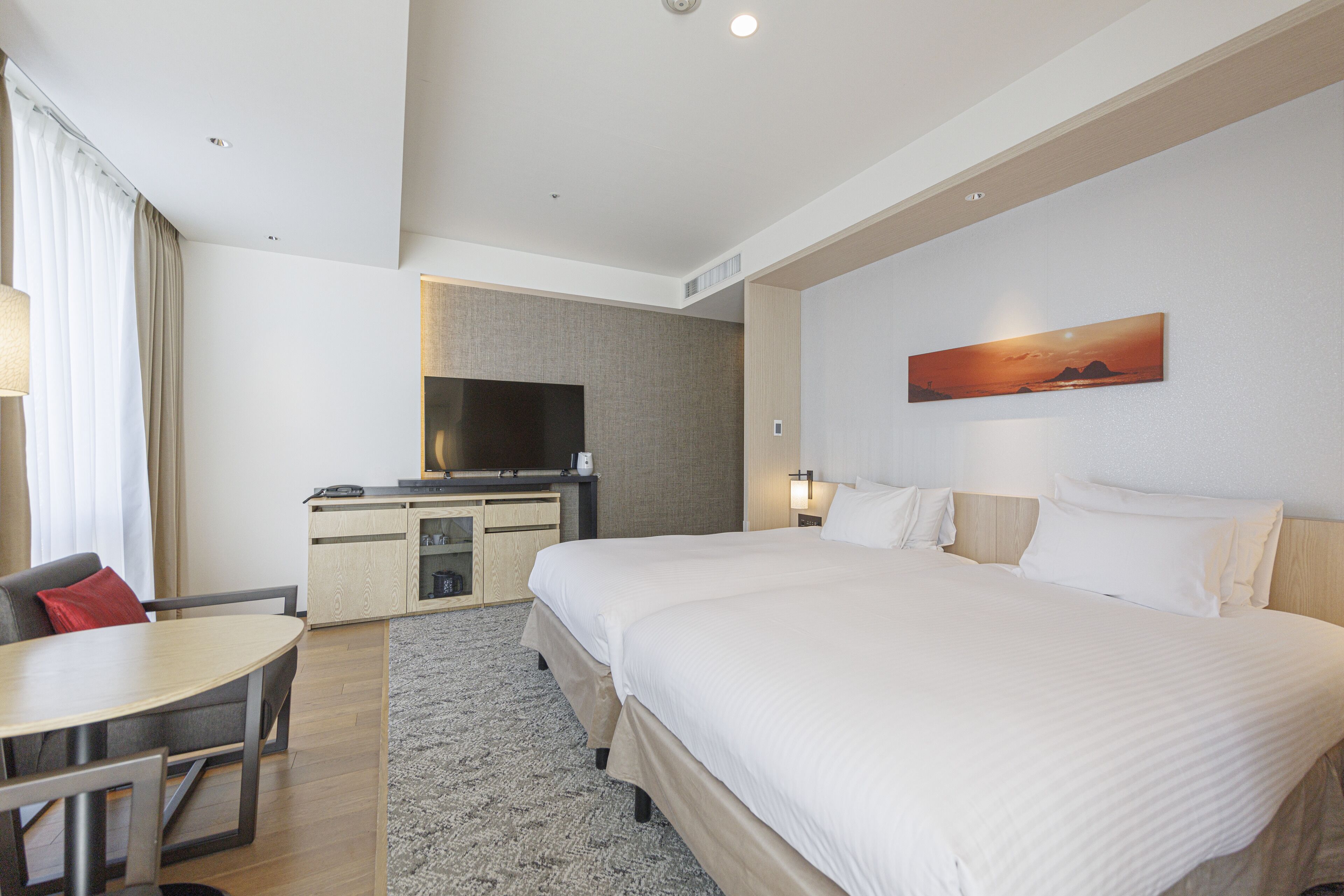 A hotel room with a large bed, a desk, a television, and a painting on the wall.