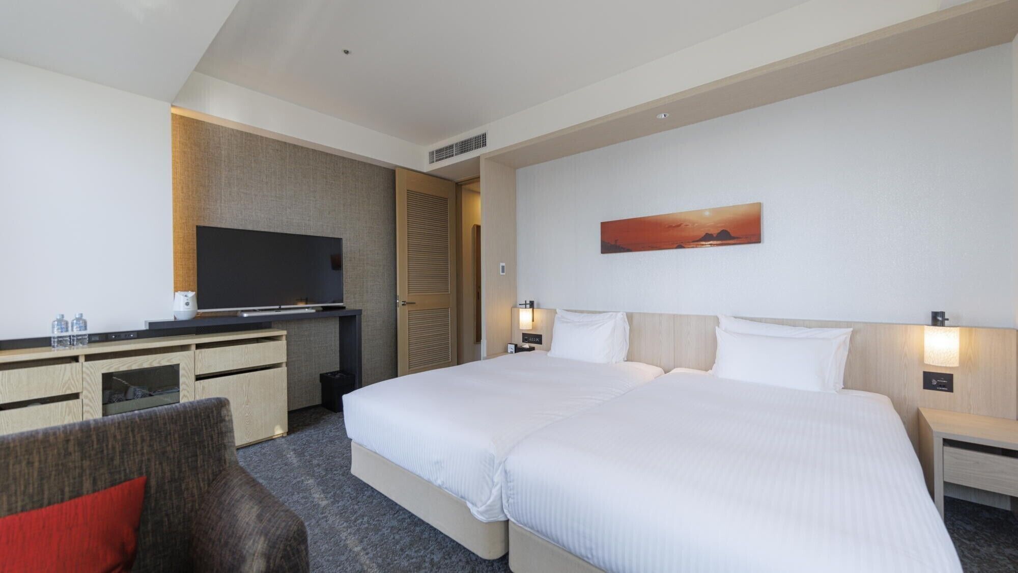 Habitación de hotel con una cama grande, televisión, escritorio y un cuadro en la pared.