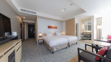 A modern hotel room with a large bed, bedside tables, a desk, and a small seating area.