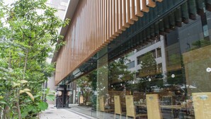 A modern building with a glass facade, wooden slats, and outdoor seating.
