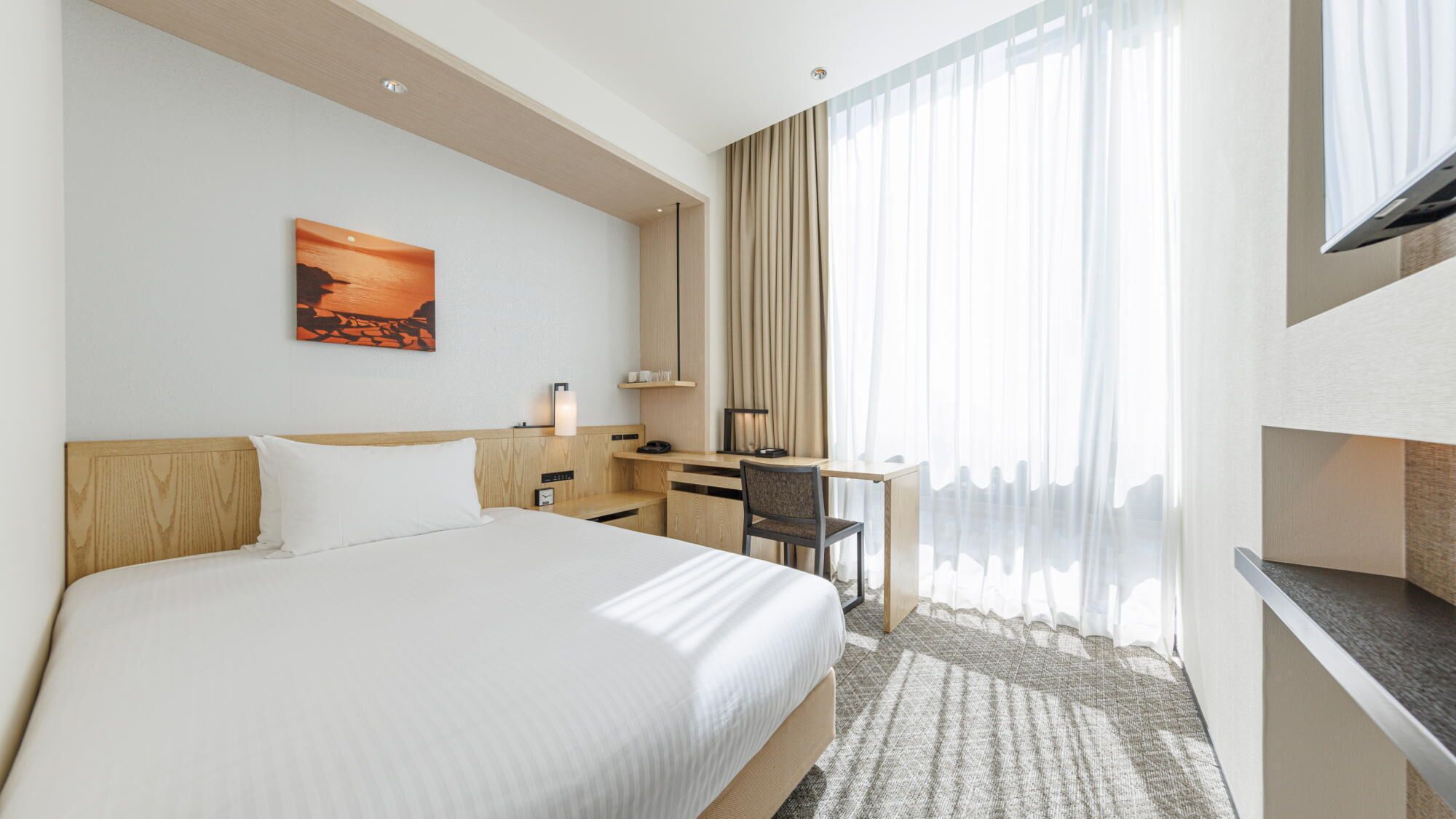 Una habitación de hotel con cama, escritorio, silla y televisor.