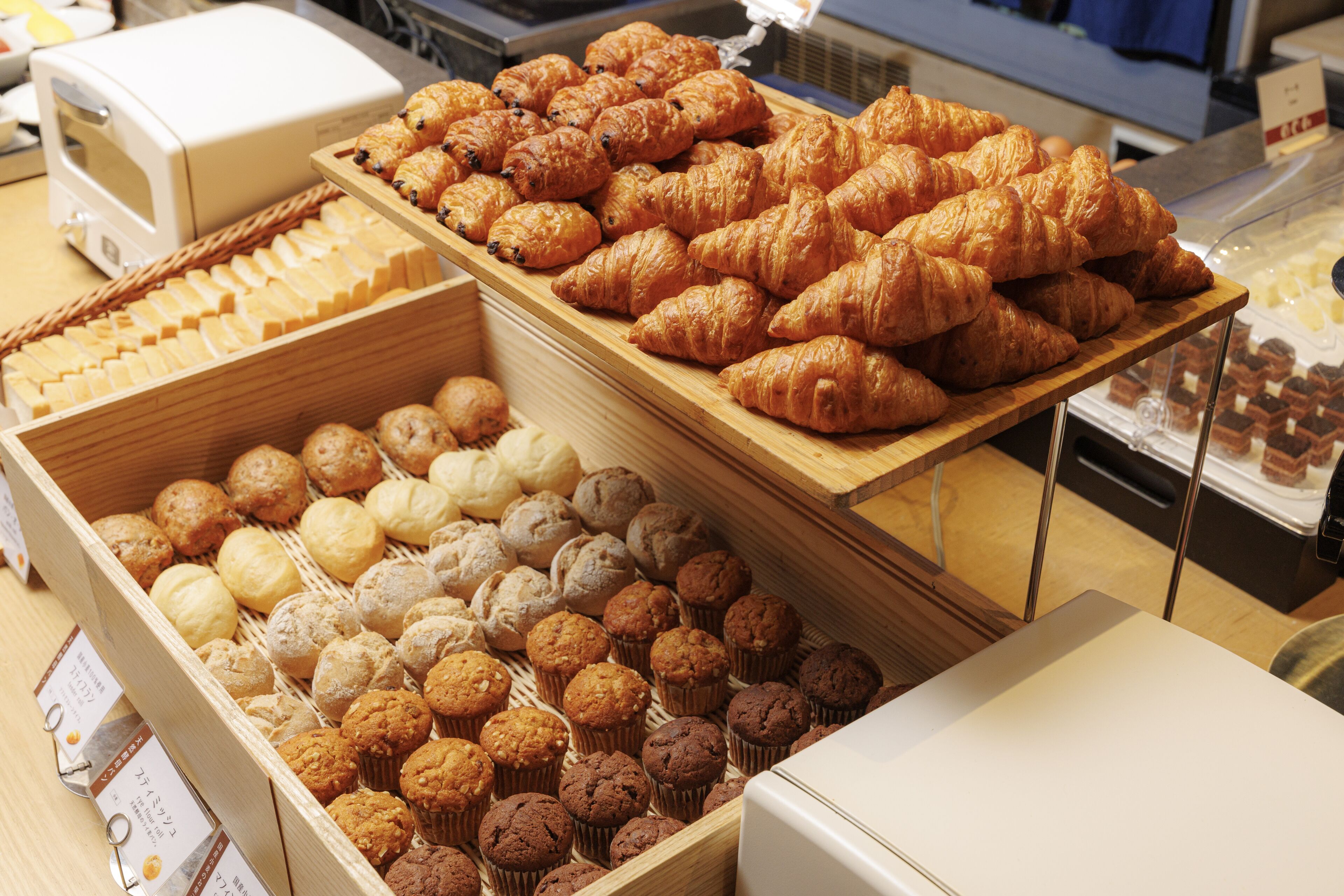 A bakery display with various baked goods including croissants, muffins, and pastries.