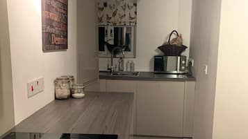 A modern kitchen with a black induction cooktop, white cabinets, and a wooden floor.