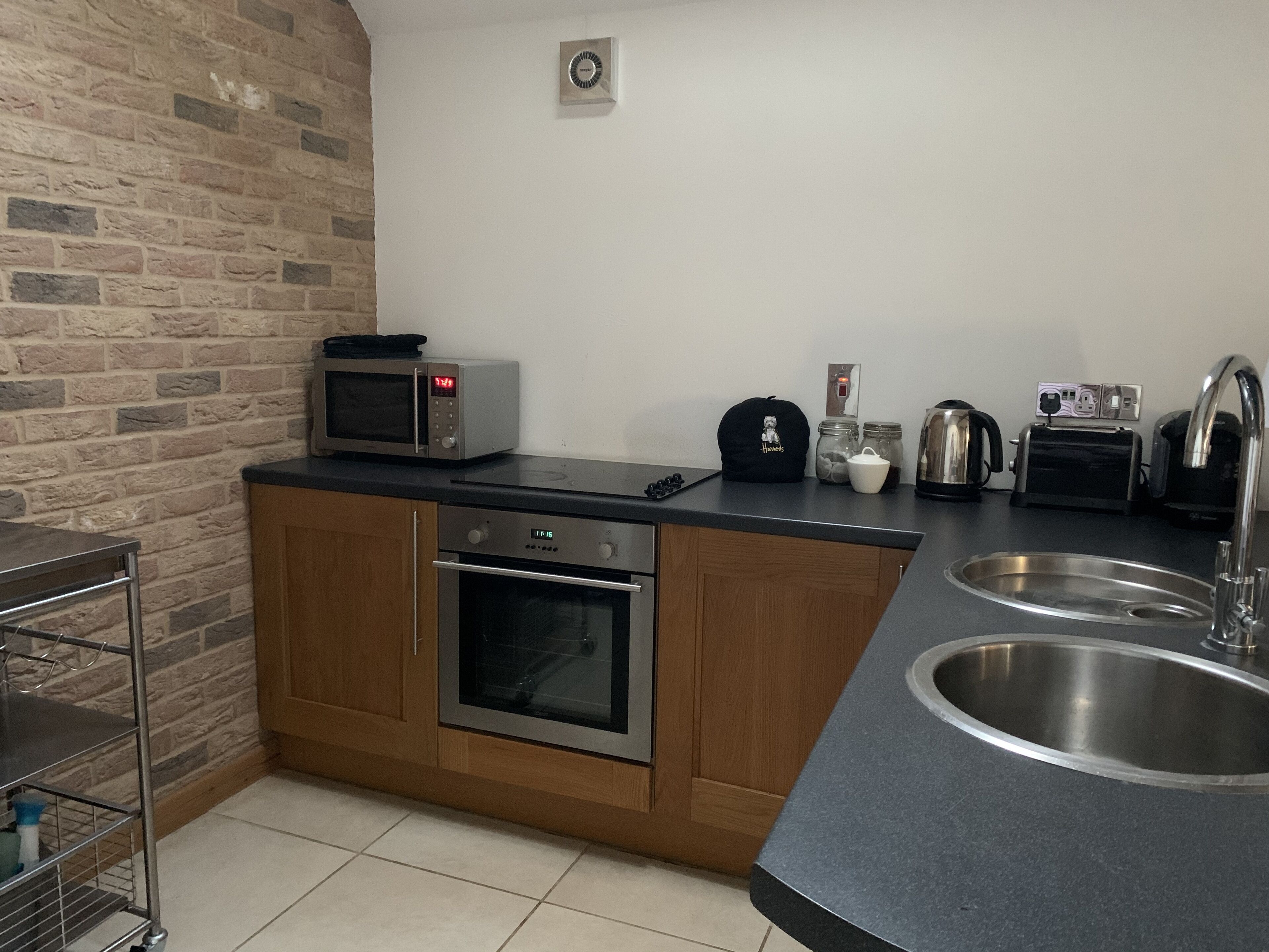 A compact kitchen with a microwave, toaster, kettle, and sink.