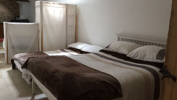 A bedroom with a bed, a bedside table, a chair, and a curtain.