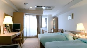A hotel room with a desk, two beds, a chair, a television, and a mirror. - Olympic Inn Kanda (Tokyo)
