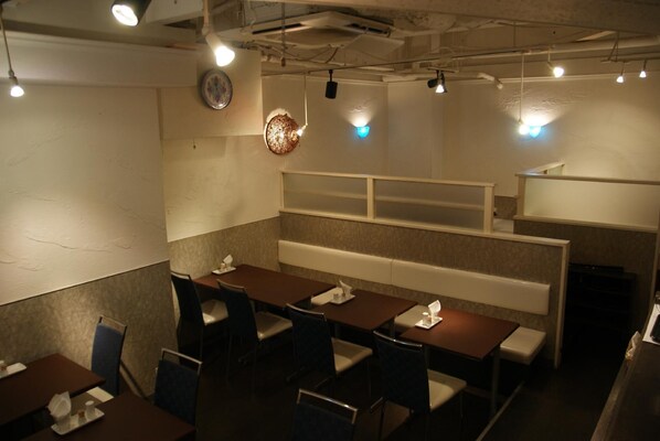 A restaurant interior with tables and chairs, a clock on the wall, and a counter area. - Olympic Inn Kanda (Tokyo)