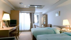 Une chambre d’hôtel avec deux lits, un bureau avec un ordinateur, une chaise, une télévision et un miroir.