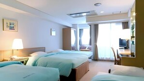 A hotel room with three beds, a desk with a computer, a chair, and a window with curtains. - Olympic Inn Kanda (Tokyo)