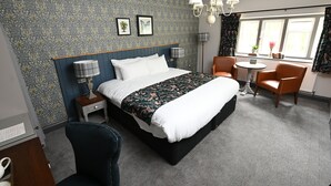 A hotel room with a large bed, two bedside tables, a chair, a small table, and a window with curtains. - The Rose Revived By Chef and Brewer Collection (Witney)