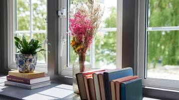 Un alféizar con libros, una planta en maceta y un jarrón con flores.