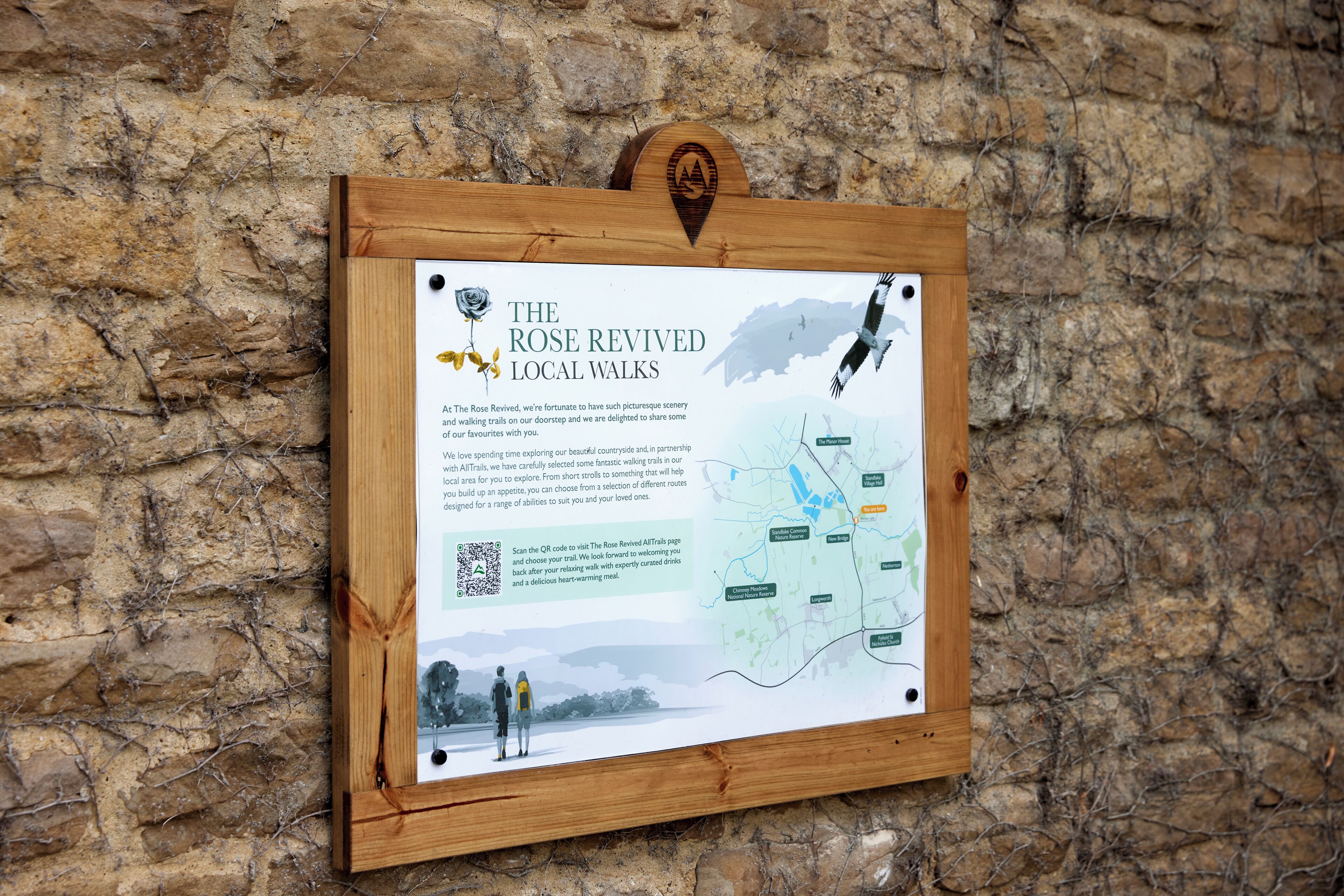 A wooden sign with a map and QR code for The Rose Revived Local Walks.