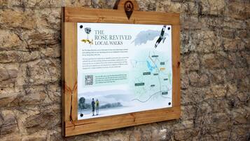 A wooden sign with a map and QR code for The Rose Revived Local Walks.