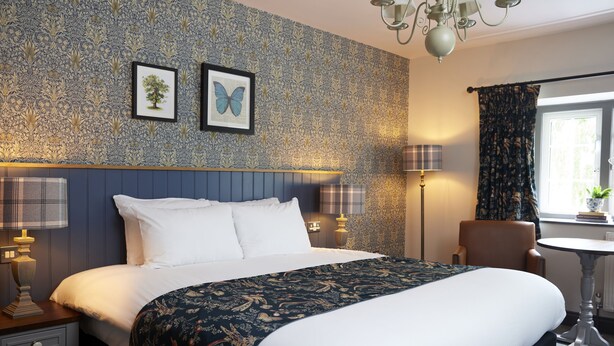 A hotel room with a large bed, a chair, a table, and a window with curtains. - The Rose Revived By Chef and Brewer Collection (Witney)