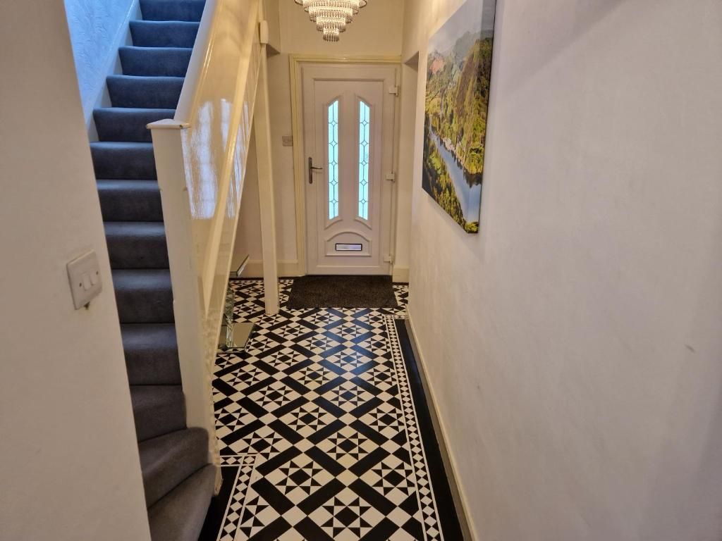 A hallway with a patterned floor, a door with glass panels, and a staircase.