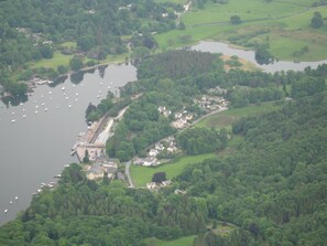 Eine Luftaufnahme einer Küstenregion mit einem Yachthafen, Wohngebäuden und umgebender Bepflanzung.