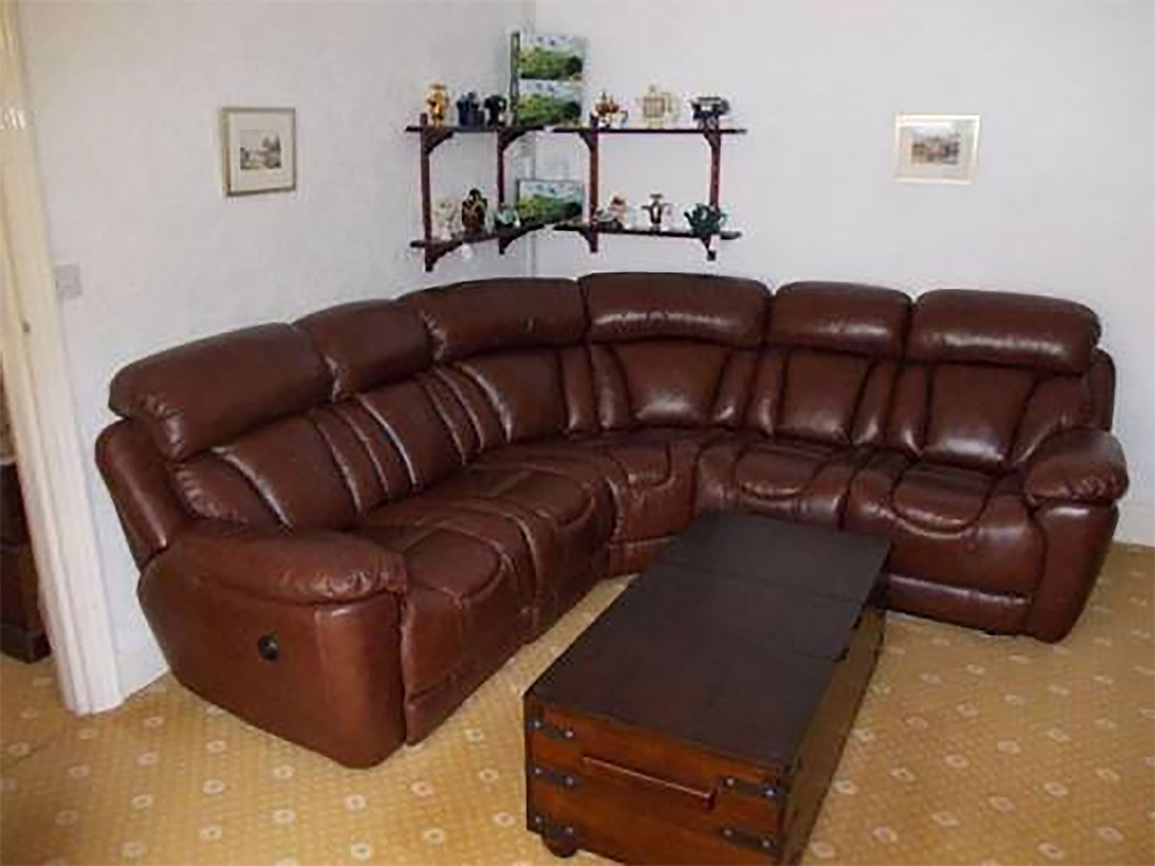 A brown leather sectional sofa with a matching ottoman in a room with patterned carpet.