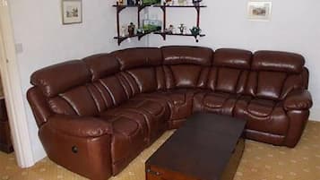 A brown leather sectional sofa with a matching ottoman in a room with patterned carpet.