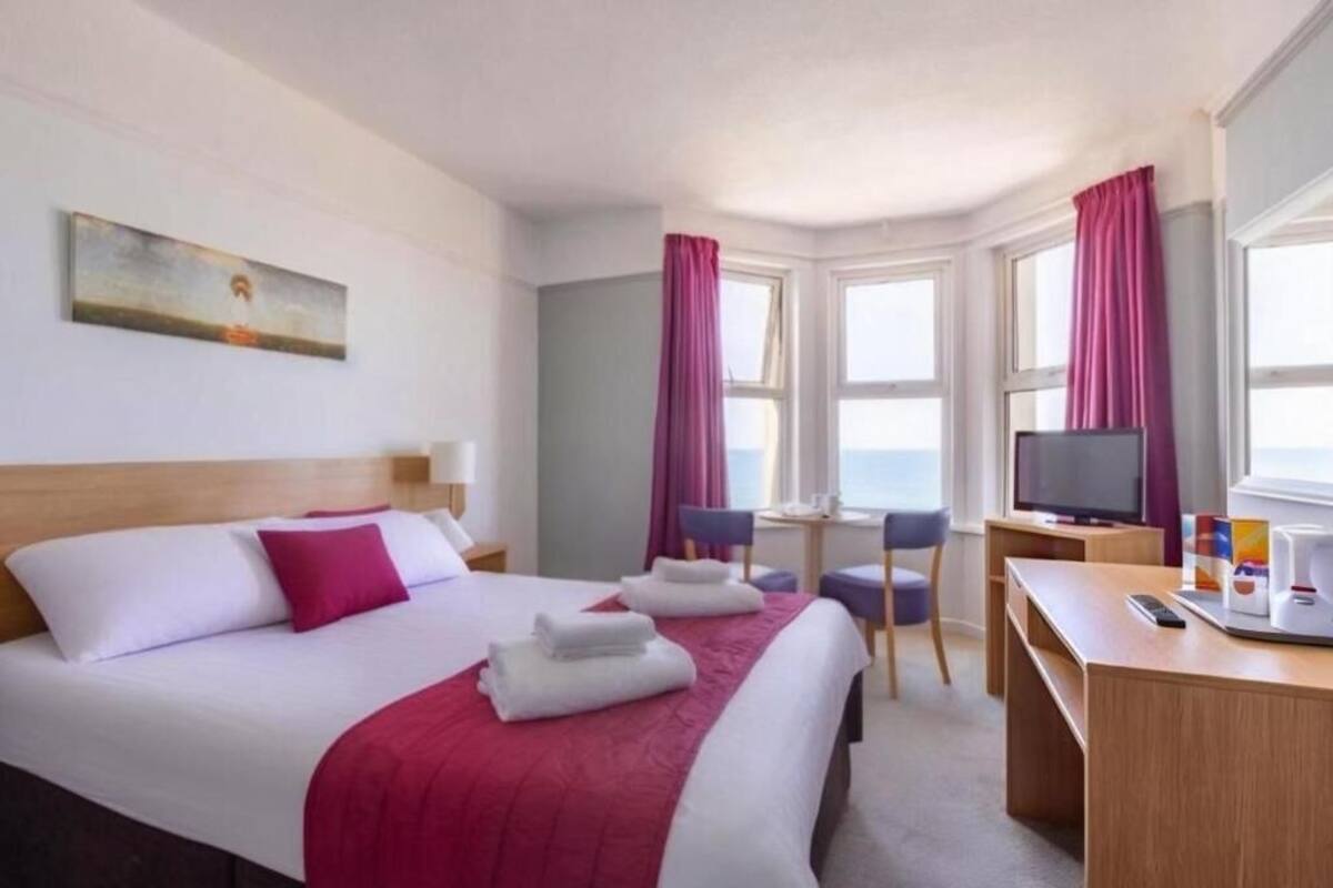 Ein Hotelzimmer mit Bett, Schreibtisch, Fernseher und einem Fenster mit Vorhängen.
