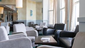 A hotel lobby with seating areas, a reception desk, and large windows with curtains. - The Beresford Hotel (Newquay)