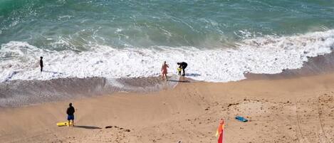 Una playa con gente, una tabla de surf y una bandera.