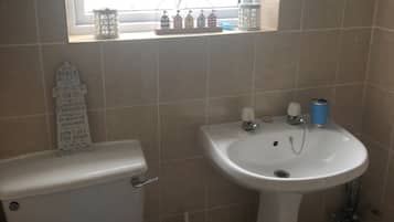 Un baño con inodoro, lavabo y ventana con vistas a la playa.