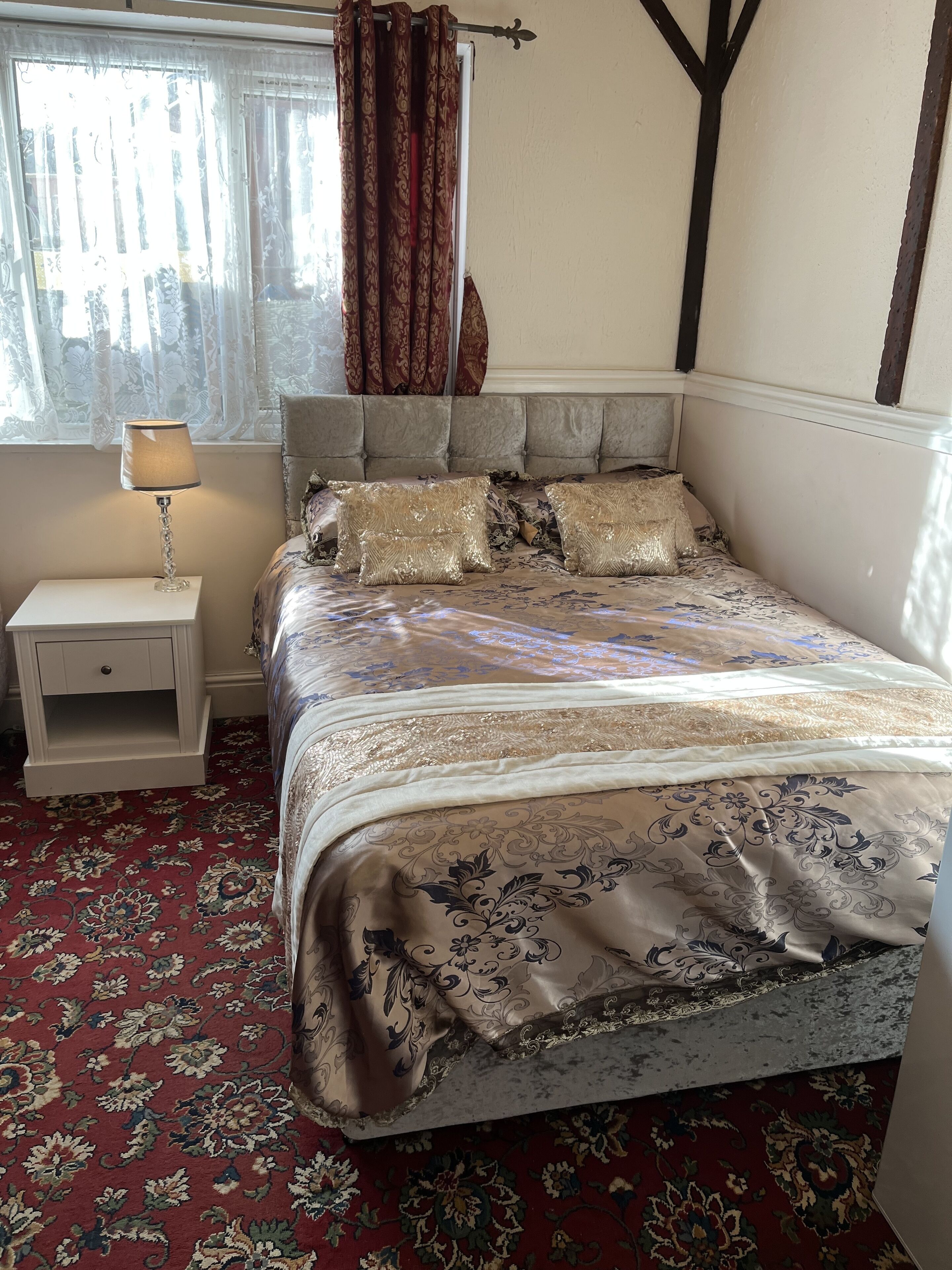 A bedroom with a bed, nightstand, and window with curtains.
