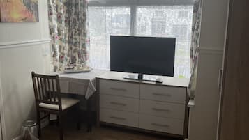 Une pièce comprenant un bureau, une chaise et un téléviseur.