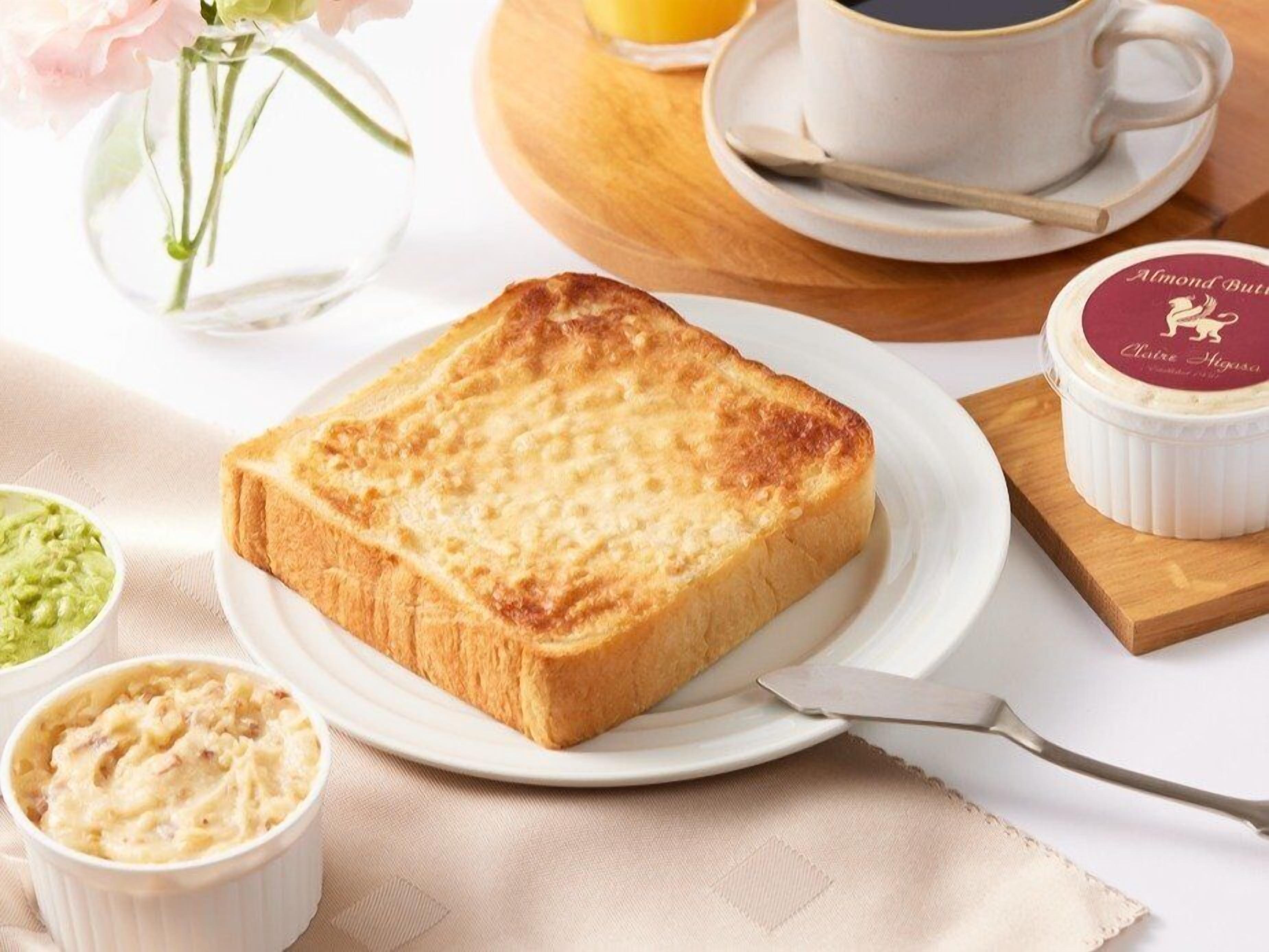 A breakfast setting with toast, coffee, and two small bowls of food, likely spreads or dips.