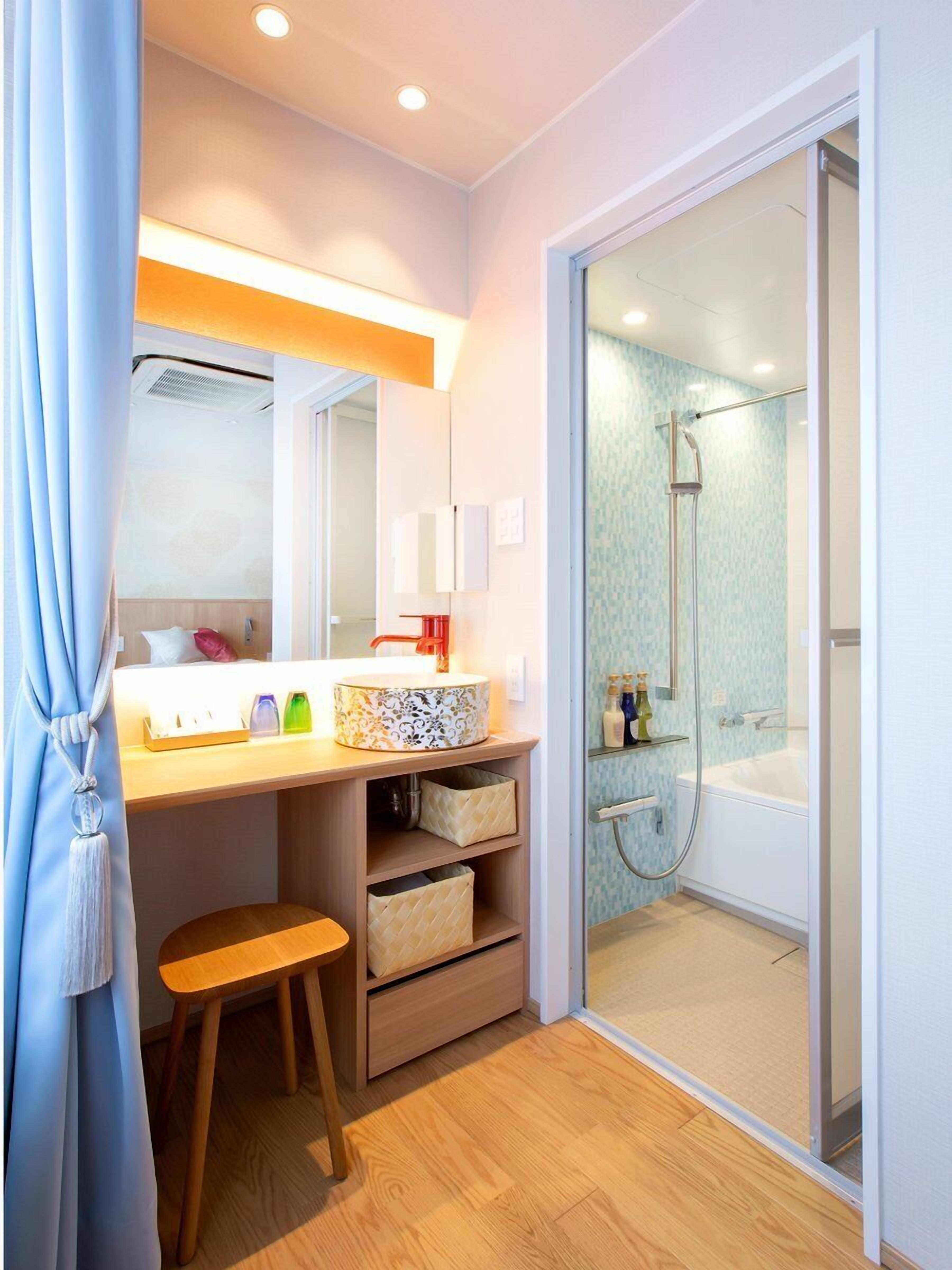 A modern bathroom with a shower, a vanity with a mirror, and a stool.