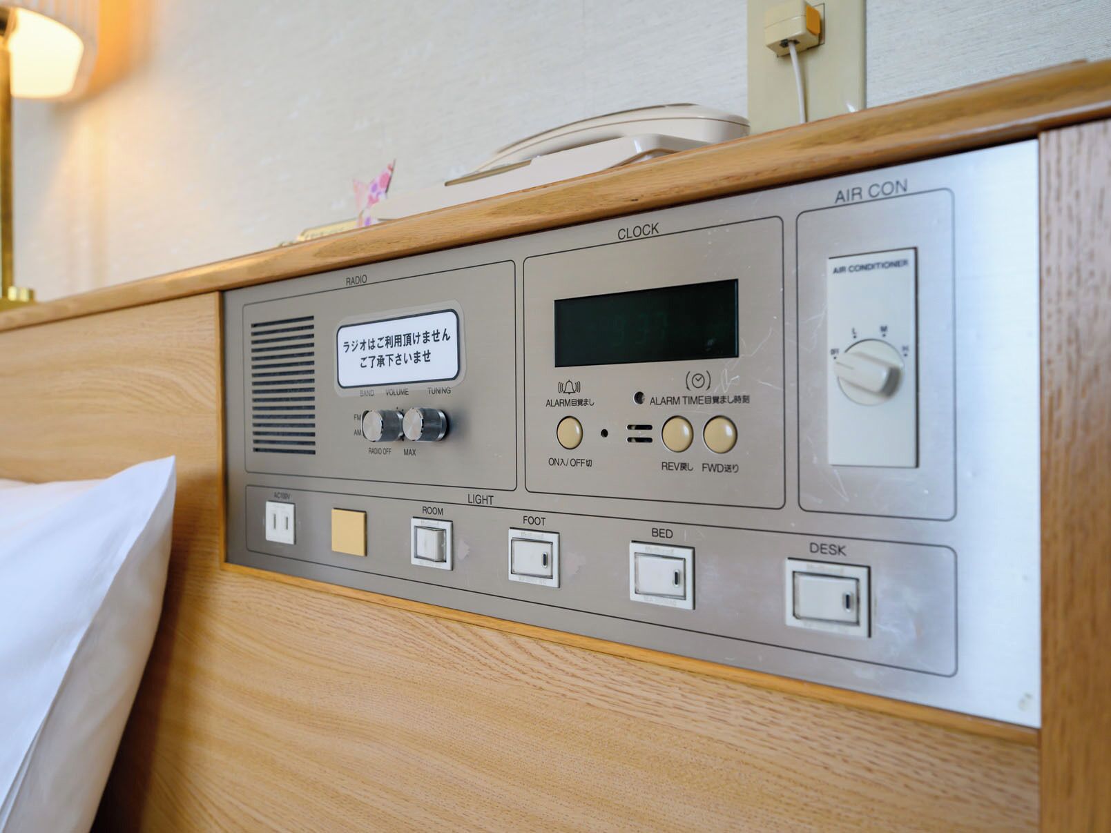 A control panel with a clock, radio, alarm, air conditioner, and light switches.