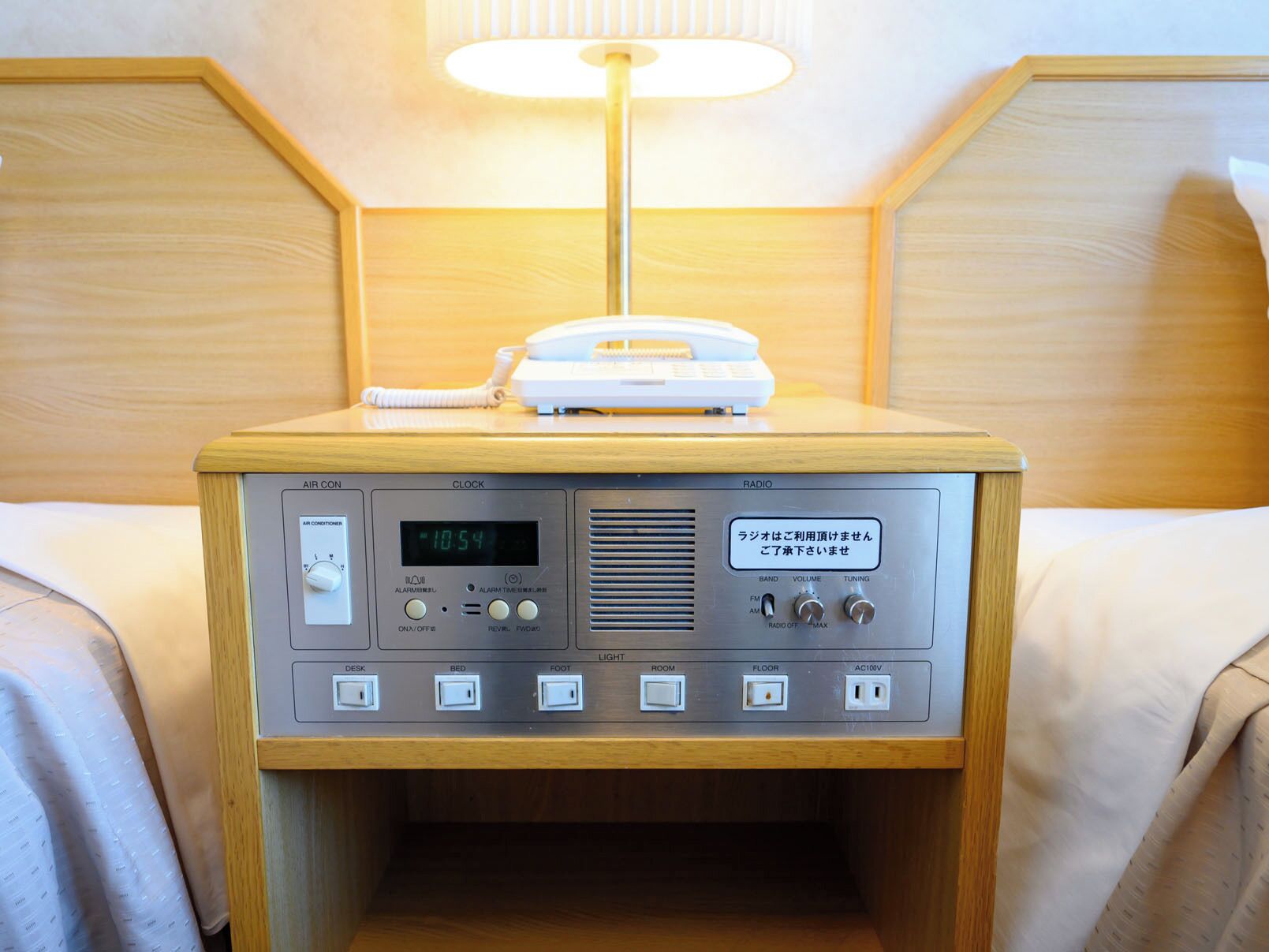 Un taulell de nit de fusta amb una ràdio, un despertador i una làmpada.