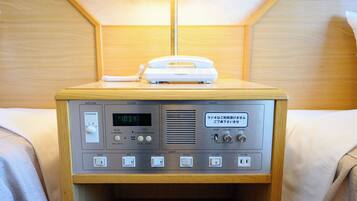 Un taulell de nit de fusta amb una ràdio, un despertador i una làmpada.