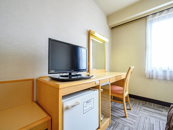 A hotel room with a wooden desk, a television, a mirror, a chair, and a mini-fridge. - Iga Ueno City Hotel (Iga)