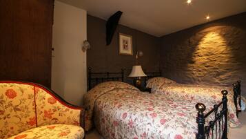 Un dormitorio con dos camas, un armario de madera, una mesita de noche con una lámpara y un cuadro enmarcado en la pared.
