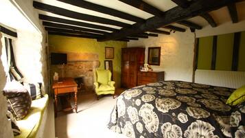 A bedroom with a bed, a wooden desk, a chair, and a television.
