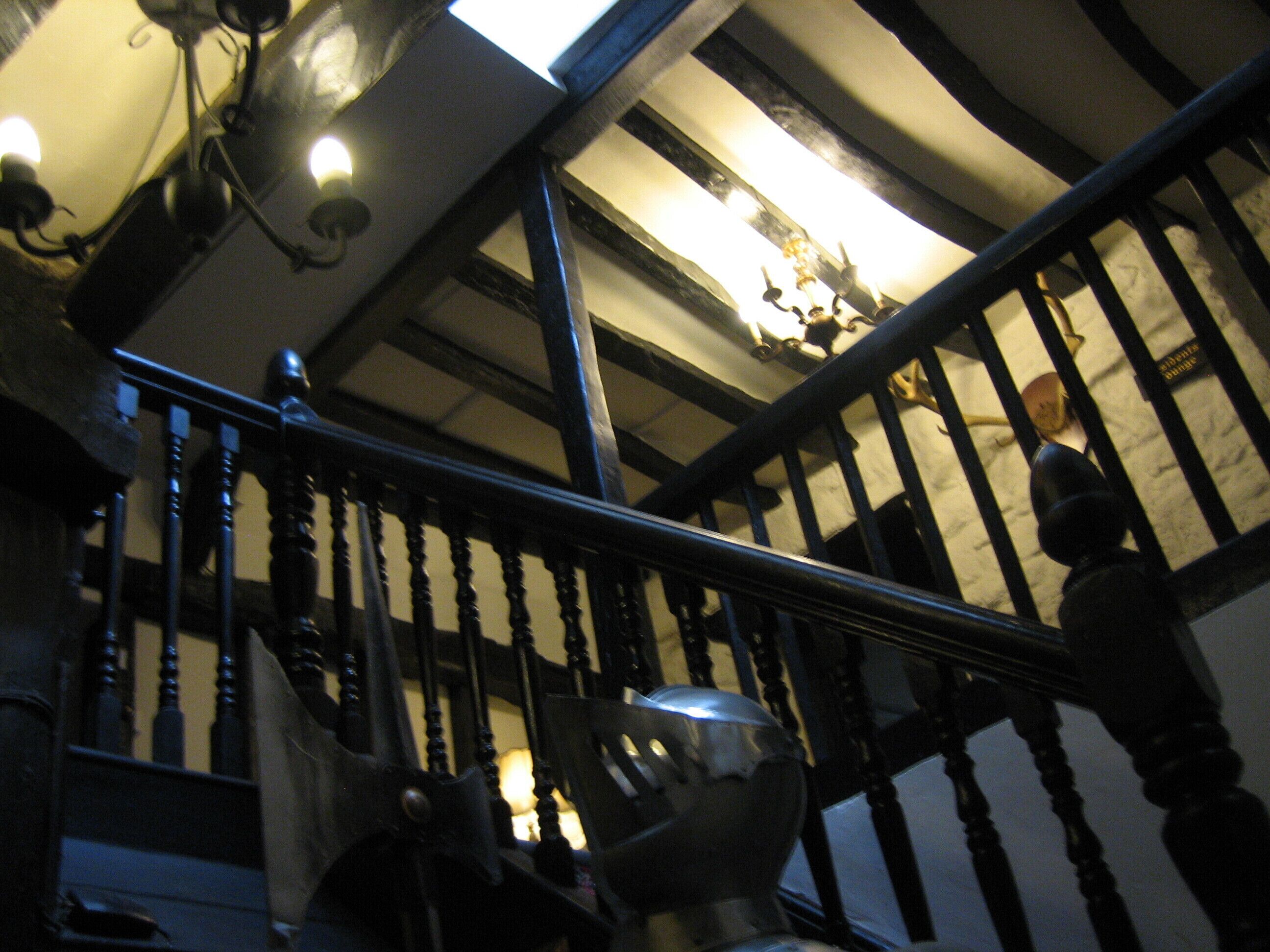 A staircase with wooden balusters and a metal handrail, leading to a landing with a chandelier.