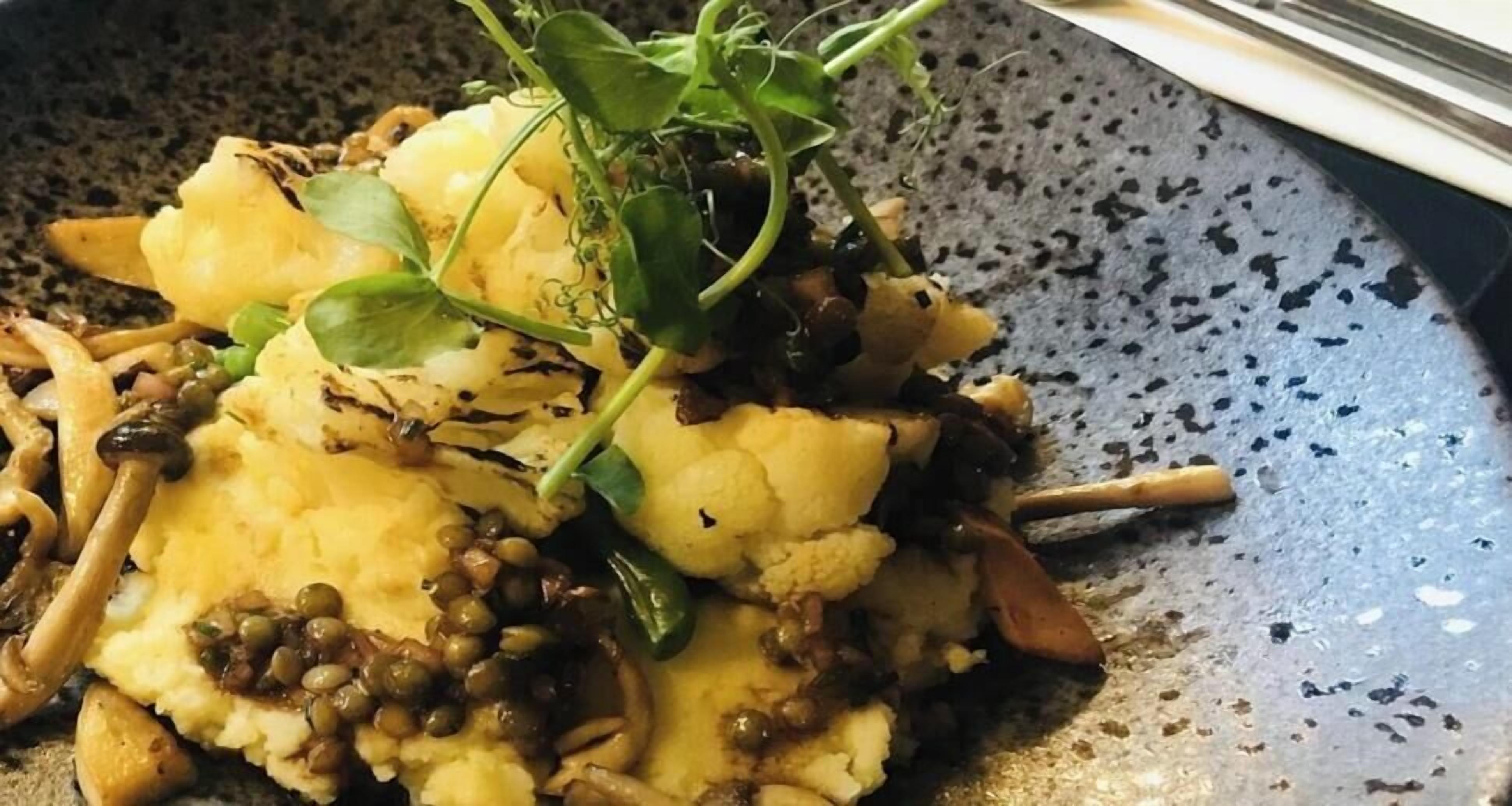Un plato con puré de papas, champiñones y vegetales verdes.