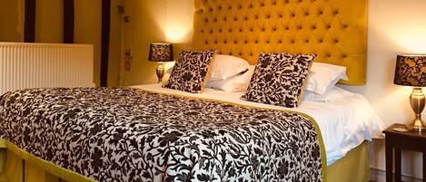 Een hotelkamer met een groot bed, een geel hoofdeinde, twee nachtkastjes met lampen en een radiator.