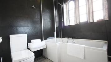 A bathroom with a white toilet, a white bathtub, and a glass-enclosed shower.