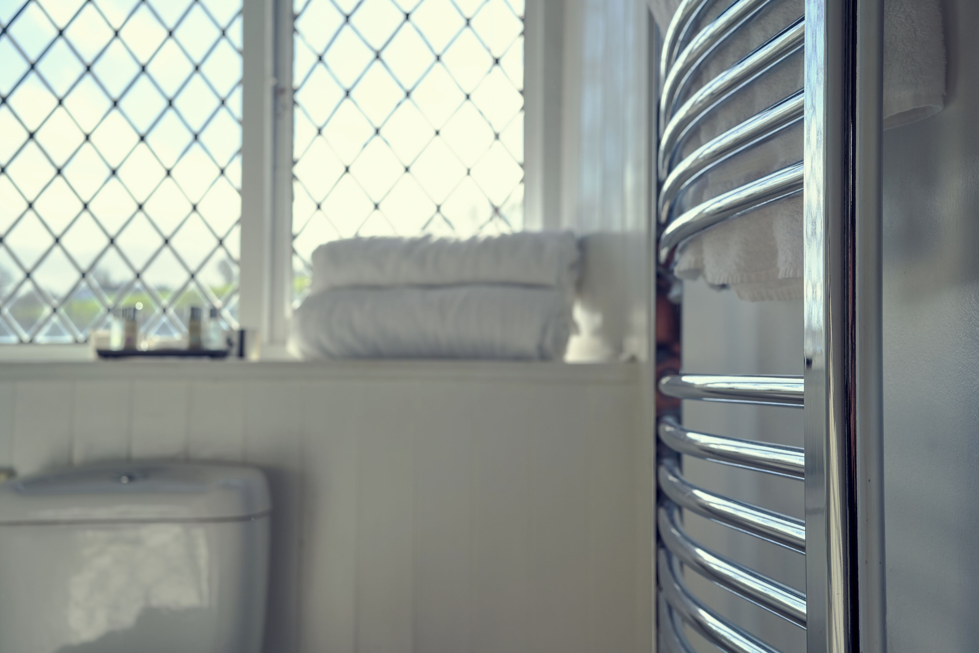 A bathroom with a window, a toilet, and a towel rack.